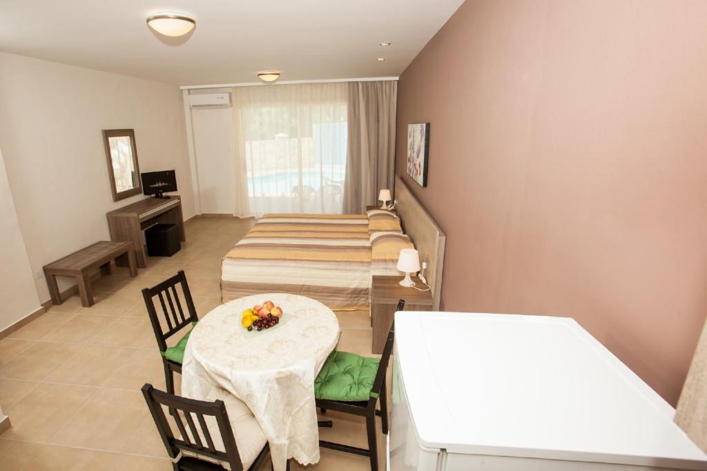 a room with four beds and a table and chairs at Crystallo Apartments in Paphos