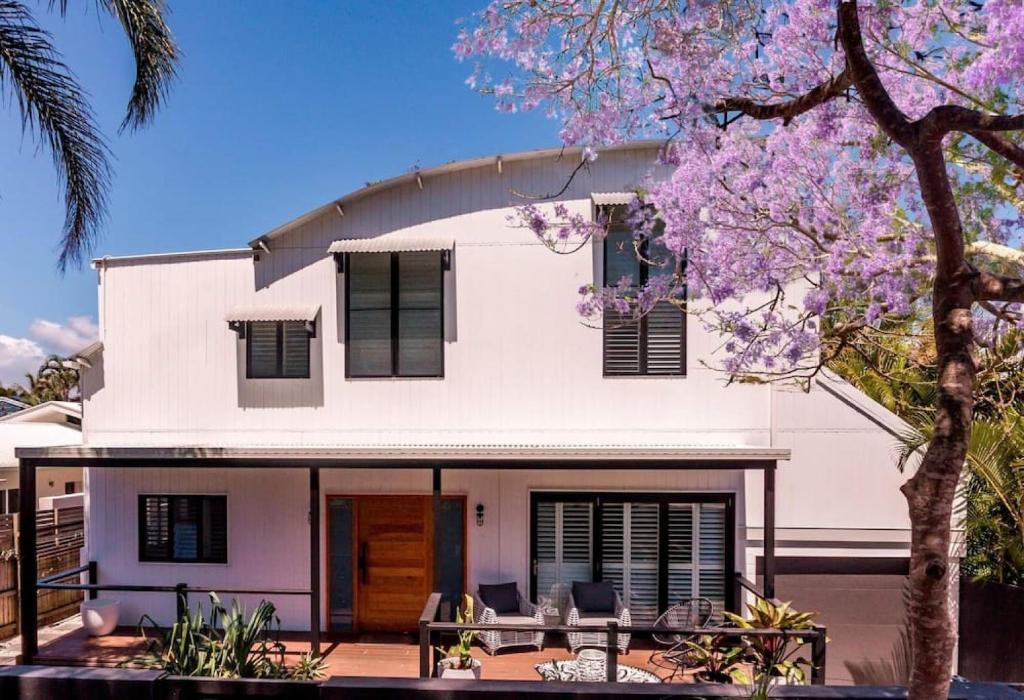 ein weißes Haus mit schwarzen Fenstern und einem Baum in der Unterkunft PACIFIC Stunning Coastal Home The Perfect Family Getaway in Sunshine Beach