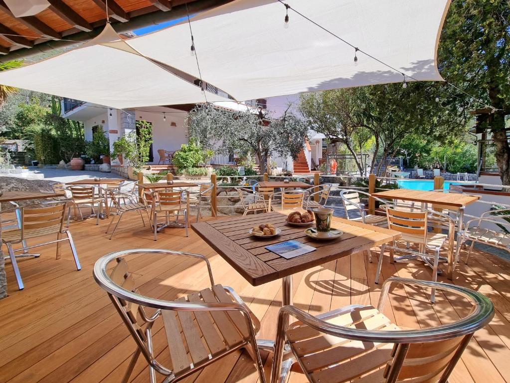 a patio with tables and chairs and an umbrella at Eco Hotel Montemerlo in Fetovaia