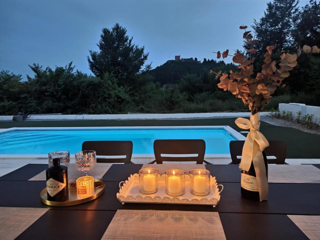 a table with candles and wine bottles and a pool at Kuća za odmor Sika in Sinj