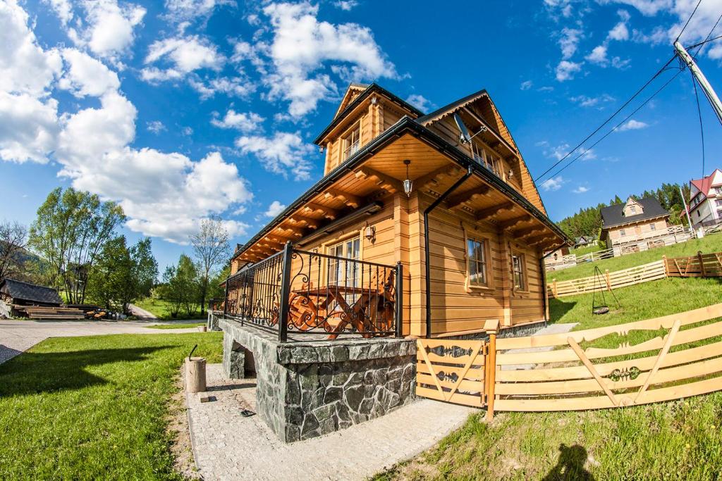 a log cabin with a balcony on a green field at Chatka Pod Laskiem - Domki w górach in Soblówka