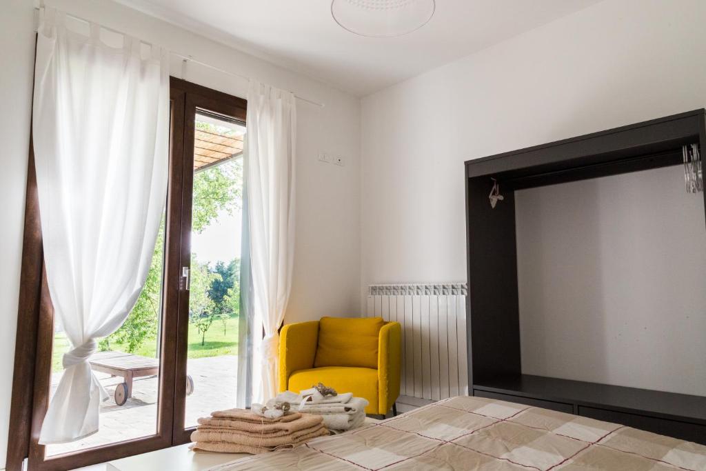 sala de estar con silla amarilla y puerta corredera de cristal en all'ombra del Bagolaro, en Taglio di Po