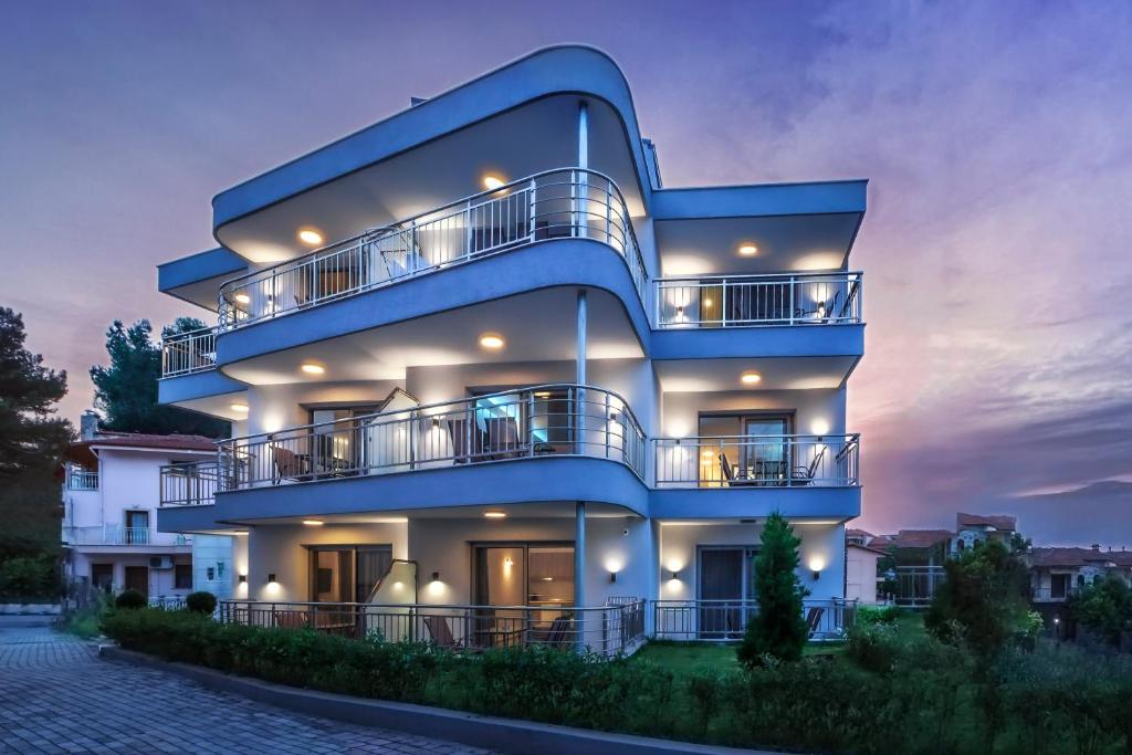 un edificio de apartamentos azul con balcones por la noche en Summer In, en Polychrono
