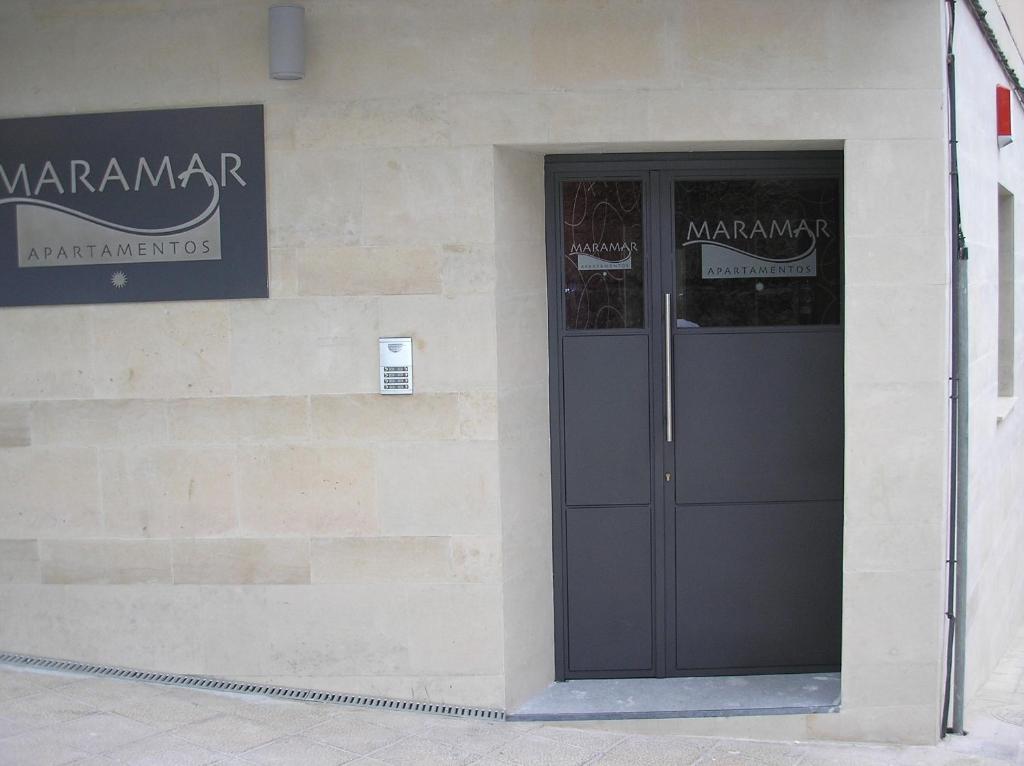 un edificio con una puerta negra a un lado. en Alojamientos Maramar, en Candás