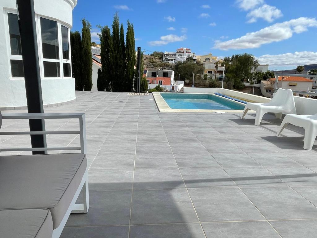 a patio with white chairs and a swimming pool at Villa Neila, Fuerteventura in Tarajalejo