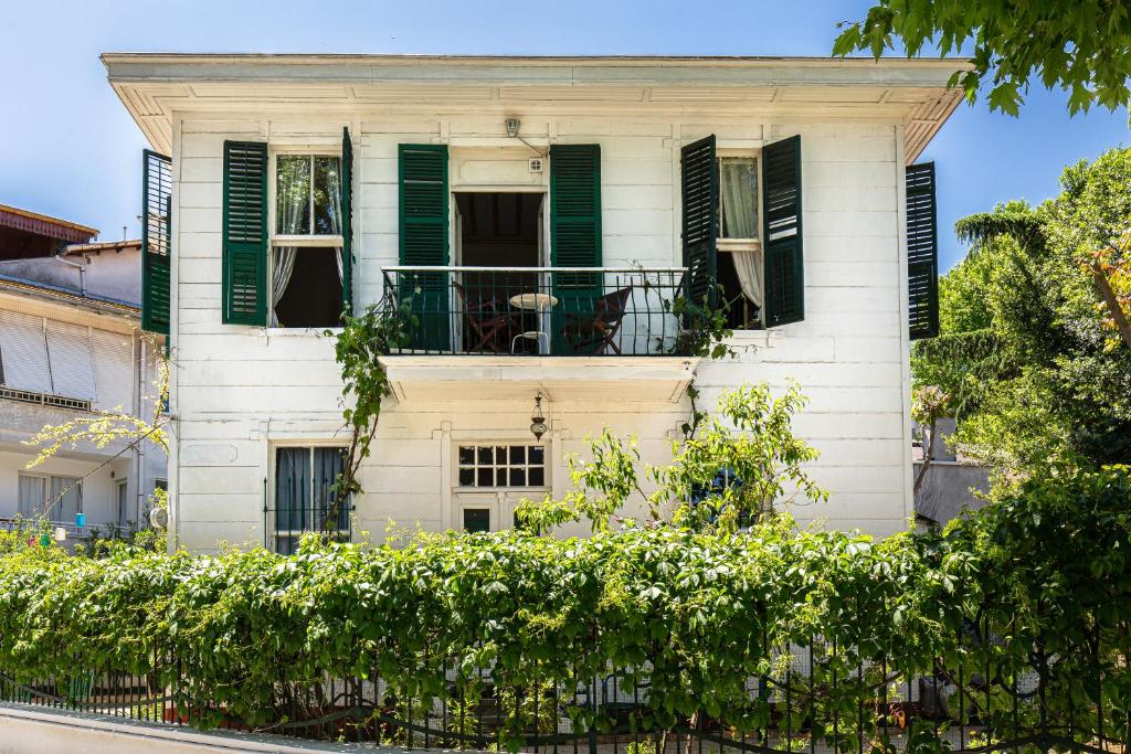 ein weißes Haus mit grünen Rollläden und einem Balkon in der Unterkunft No16 Ada in Adalar