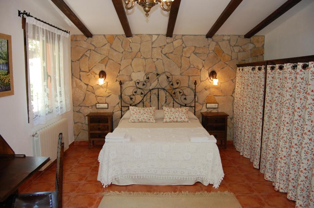 1 dormitorio con cama y pared de piedra en Casa Rural Los Nogales en Bogarra