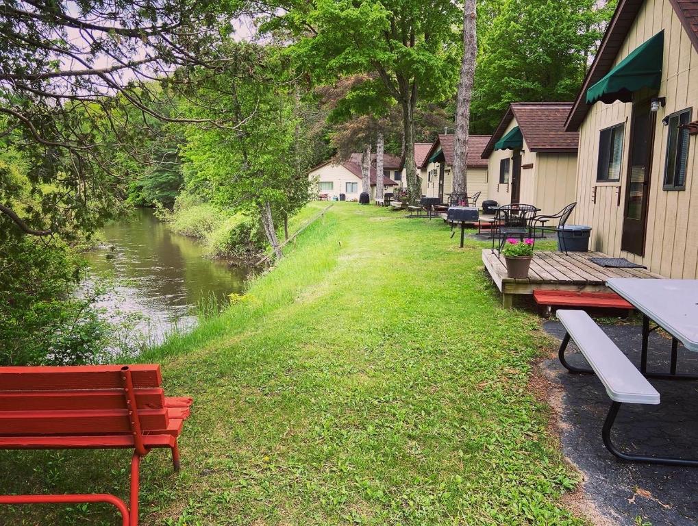 a row of tables and benches next to a river at Betsie Riverside Resort in Benzonia