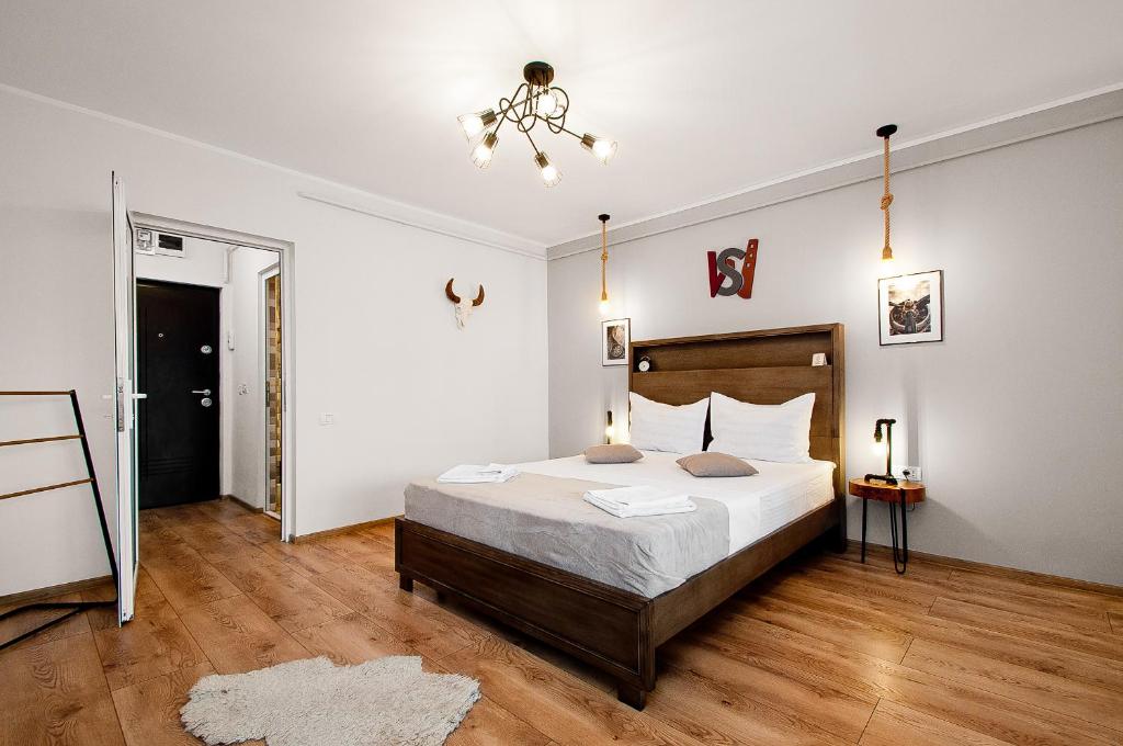 1 dormitorio con cama y lámpara de araña en Wood&Steel Apartment, en Galaţi