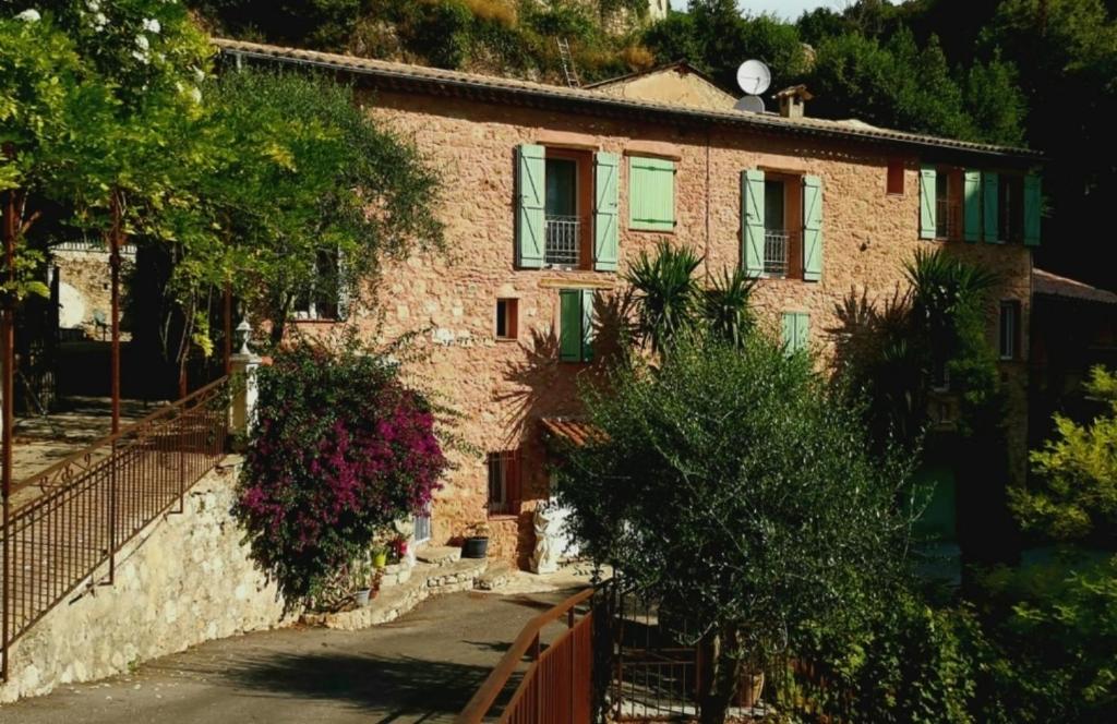 een stenen huis met groene ramen en een hek bij Appartement dans ancien moulin à huile rénové in Grasse