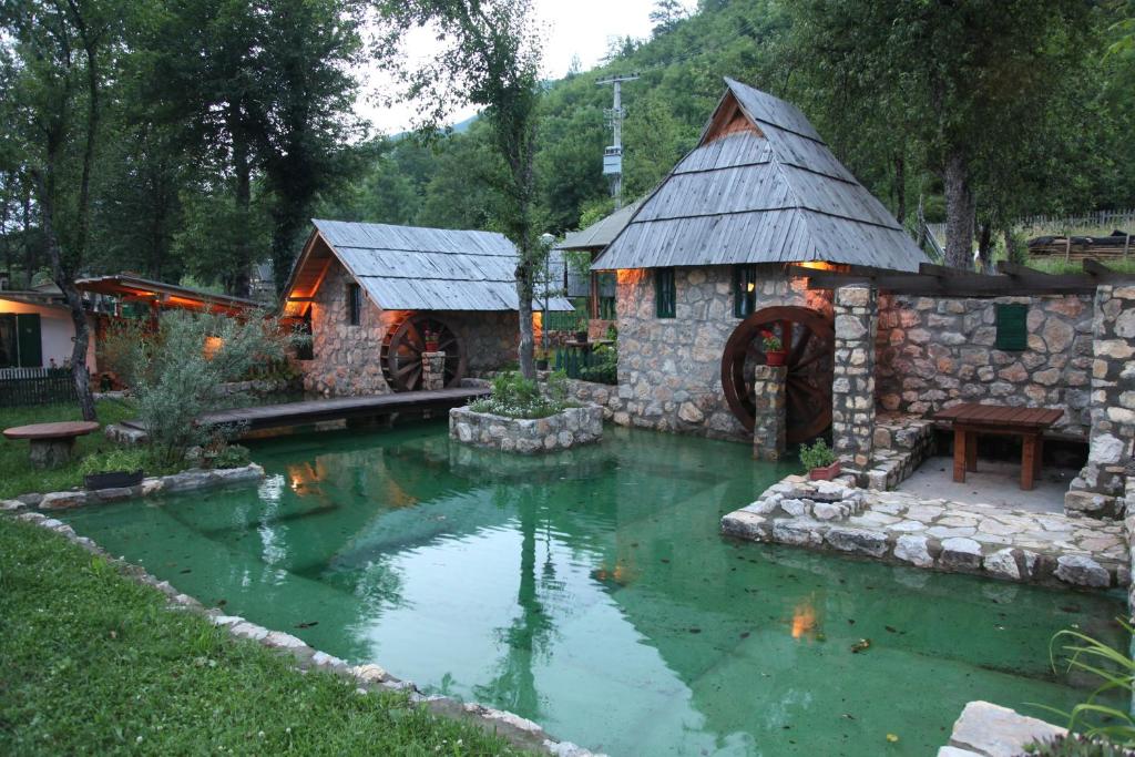 a pond in a yard with a small house at Rafting Camp Tara Center Tri Vodenice in Bastasi