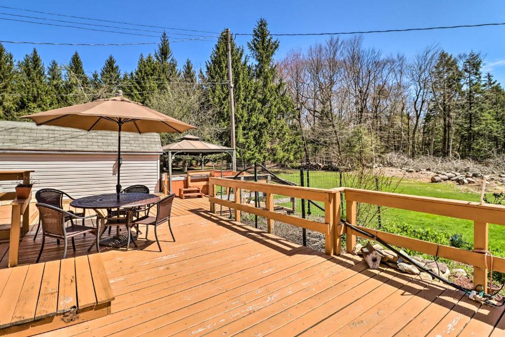 une terrasse en bois avec une table et un parasol dans l'établissement Spacious Tobyhanna Home and Guest Home 3 Mi to Lake, à Tobyhanna