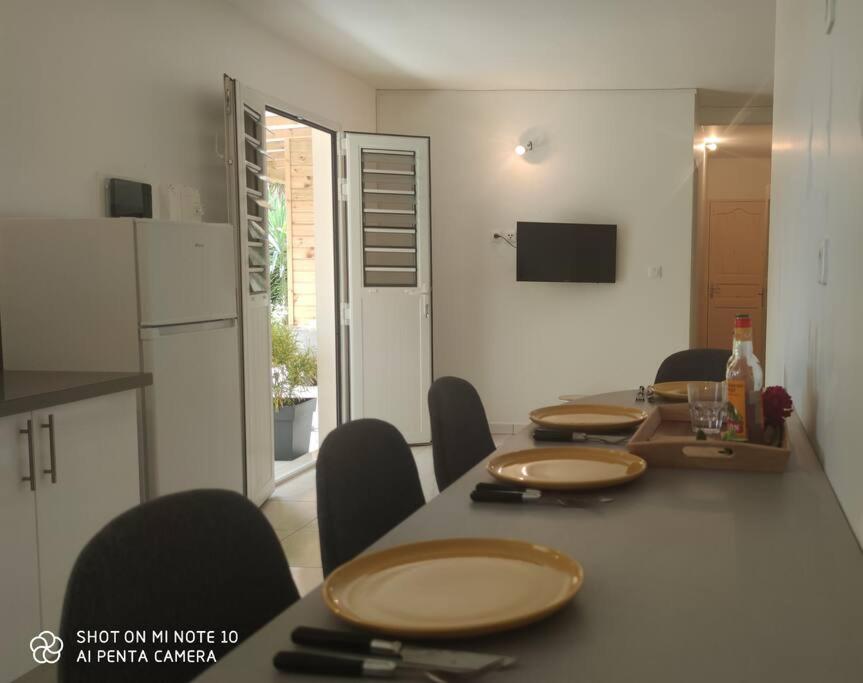 een eetkamer met een tafel met stoelen en een keuken bij Villa tropicale charmant T2 dans un cadre verdoyant in Gros-Morne