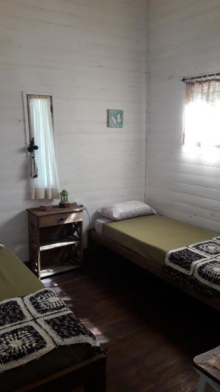 a room with two beds and a table and a window at Cabaña de las mariposas in Tigre