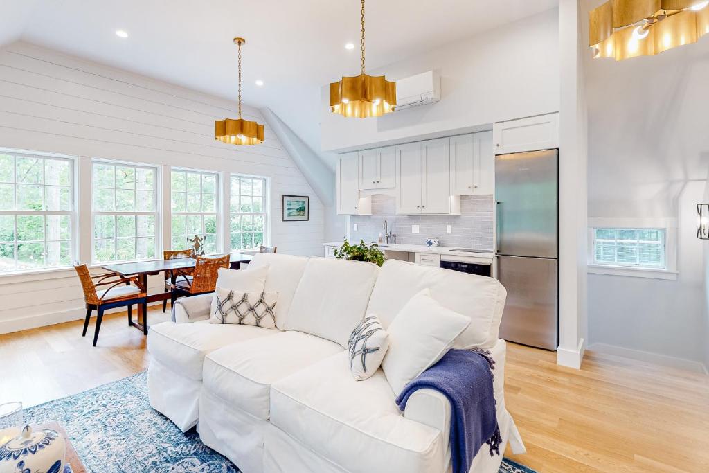 a living room with a white couch and a kitchen at Coveside Carriage House in Boothbay Harbor