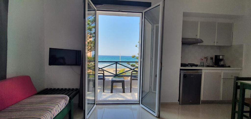 a living room with a sliding glass door with a view of the ocean at Stella Apartments in Kokkini Khanion