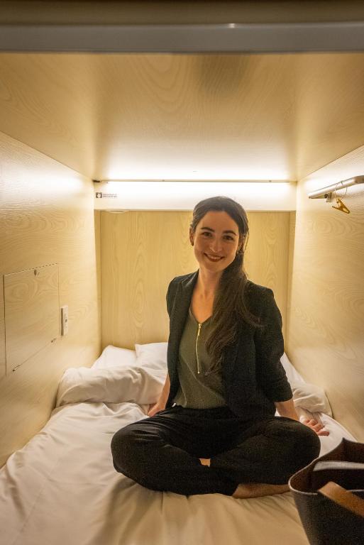 a woman sitting on top of a bed at Panda Pod Hotel in Richmond