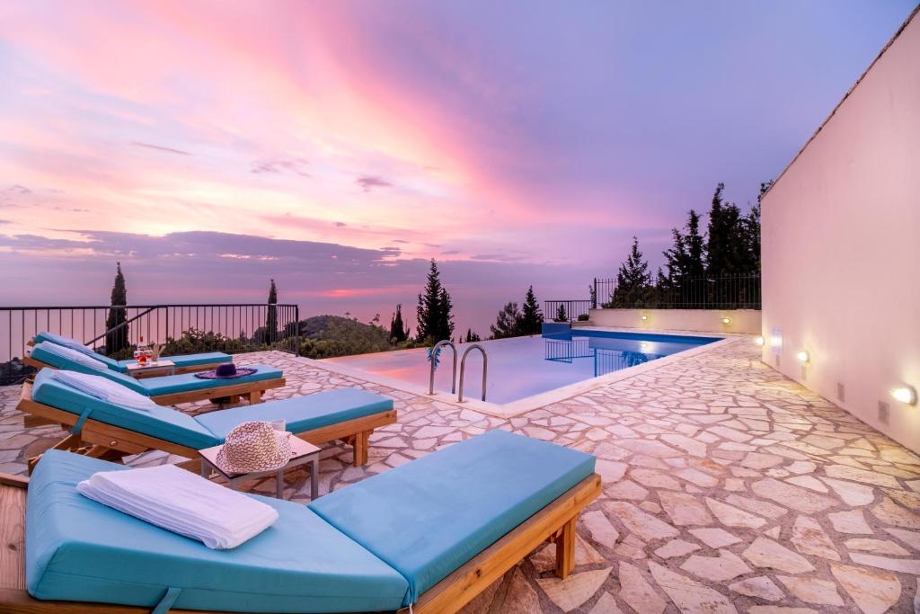 un patio con sofás azules y una piscina en Endless Blue Villa Lefkada, en Kalamitsi