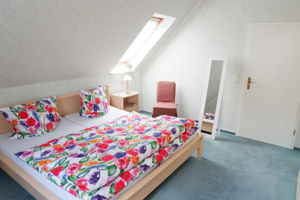 - une chambre avec un lit doté d'une couverture colorée et d'une chaise dans l'établissement Ferienwohnung Ostfriesenglück, à Leer