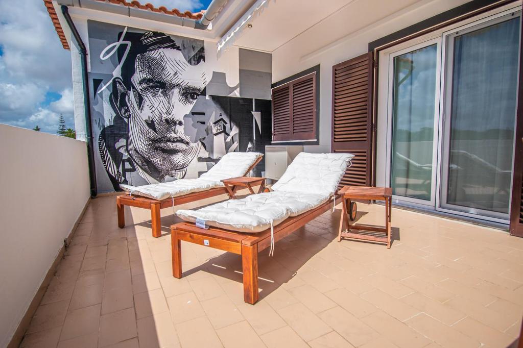 キンタ・ド・ラーゴにあるApartment close to golf, beaches, Quinta Lago, Vale Lobo, Quarteira and Vilamouraの壁にベンチ2台と壁画が備わる部屋