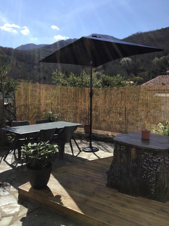 un patio con mesa y sombrilla en Belle maison de montagne proche Ajaccio, en Bastelica