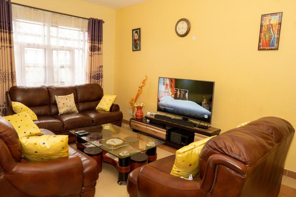 un soggiorno con mobili in pelle e TV di Bonaventure Apartment a Kisumu