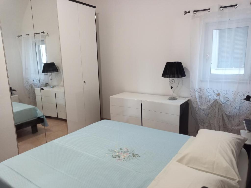 een witte slaapkamer met een bed en een spiegel bij Casa Santa Chiara in Mola di Bari