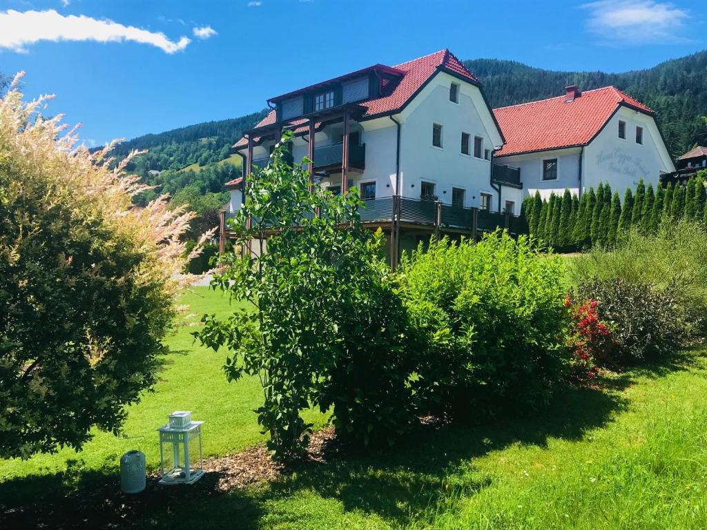 a large white house in a green field with trees at Wohlfühlpension Kreischberg in Sankt Georgen ob Murau