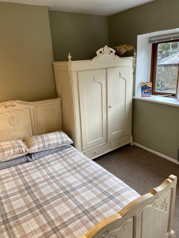 a bedroom with a bed and a cabinet and a window at Calderside Cottage (2 BDR Central Hebden Bridge) in Hebden Bridge