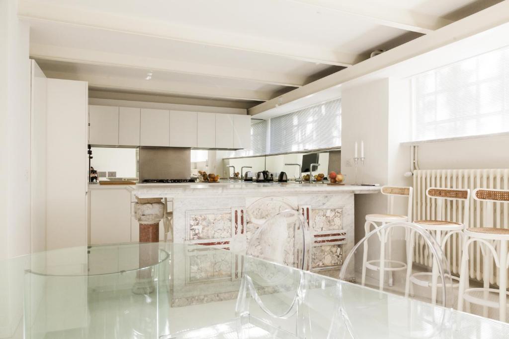 a white kitchen with a glass table and chairs at Sant'Agnese DOMUS in Milan