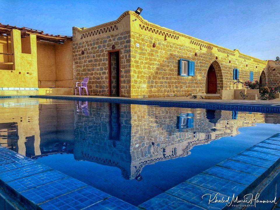 a swimming pool in front of a brick building at Tebtunis in ‘Izbat an Nāmūs
