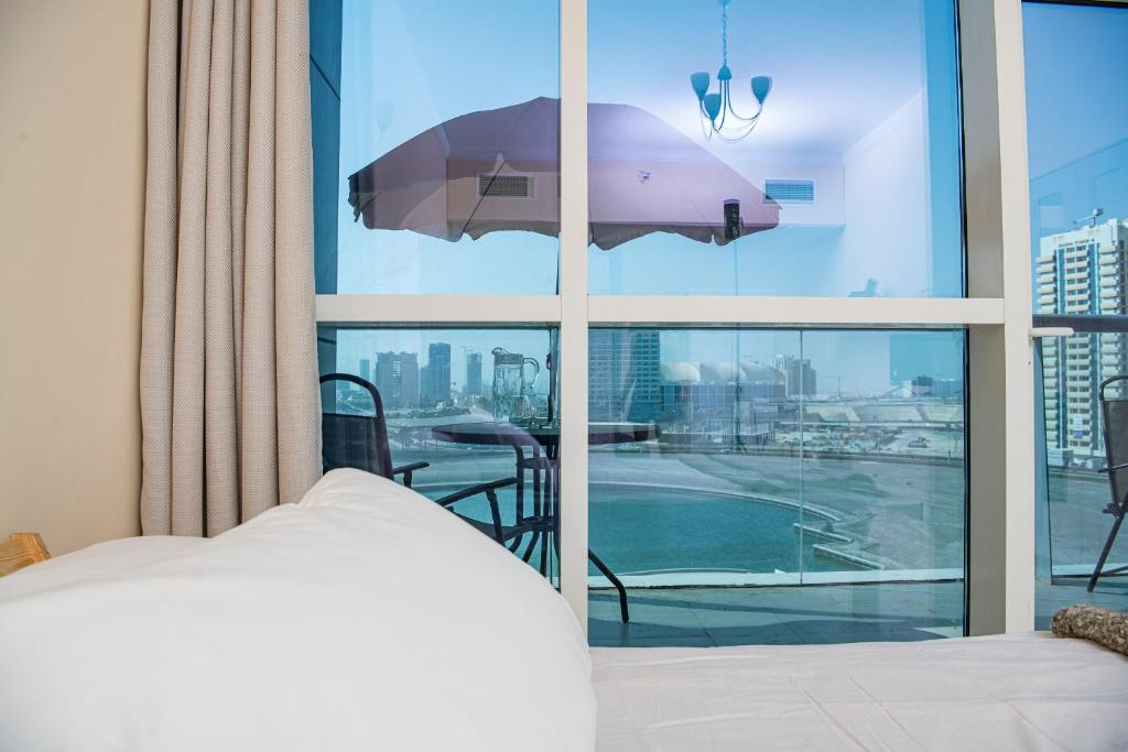 a bedroom with a bed and a balcony with an umbrella at Studio in the heart of Sports City -great view & amenities! in Dubai