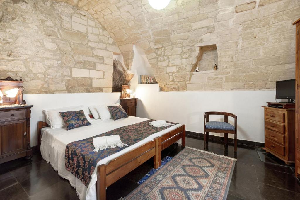 ein Schlafzimmer mit einem Bett und einer Steinmauer in der Unterkunft Locanda La Meridiana in Ragusa