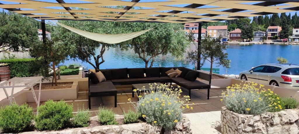 un patio con un sofá, una hamaca y un lago en Apartments Villa Judita, en Blace