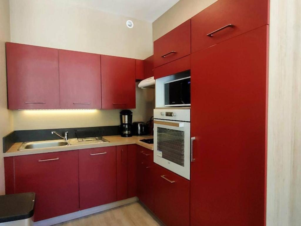a kitchen with red cabinets and a sink at Appartement Cauterets, 3 pièces, 6 personnes - FR-1-234-172 in Cauterets