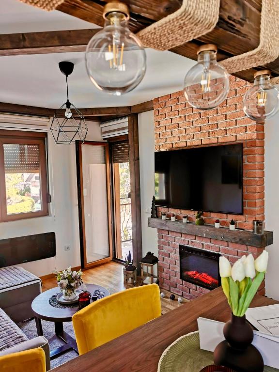 a living room with a fireplace and a tv at Zlatiborske Noći in Zlatibor
