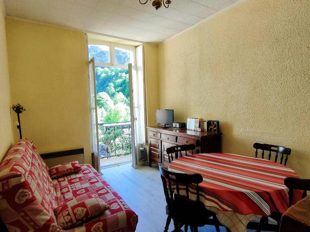 Cette chambre comprend une table, un canapé et une fenêtre. dans l'établissement Charmant 2 Pièces 4/6 Pers Centre Ville, Balcon, Cuisine Équipée, Parking - FR-1-234-130, à Cauterets