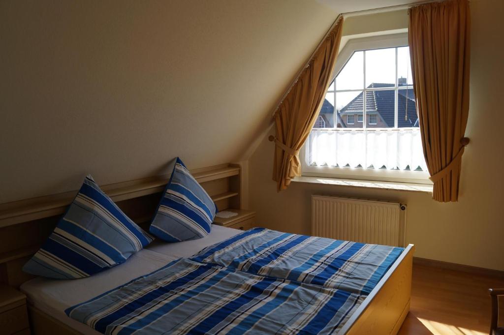 een slaapkamer met een bed met blauwe kussens en een raam bij Haus Katharina Ferienwohnung 1 in Cuxhaven
