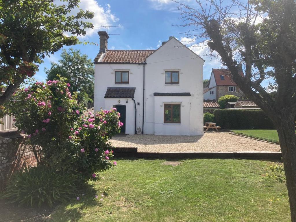ein weißes Haus mit einem Garten und Blumen in der Unterkunft Wensum Cottage in Norwich
