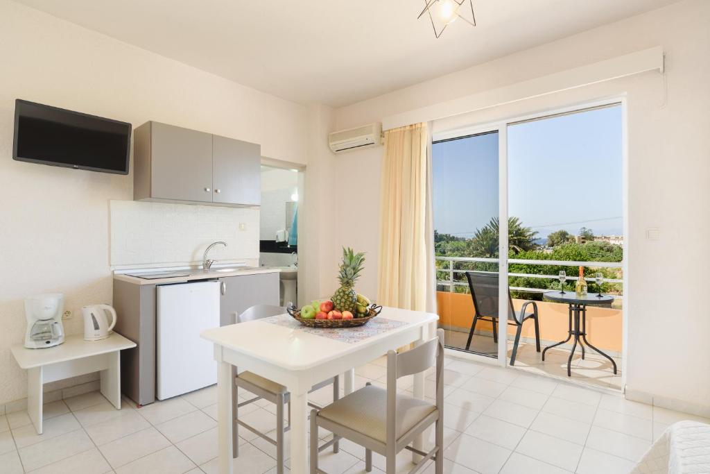 a kitchen and dining room with a view of a balcony at Eugenia Studios & Apartments in Ialyssos