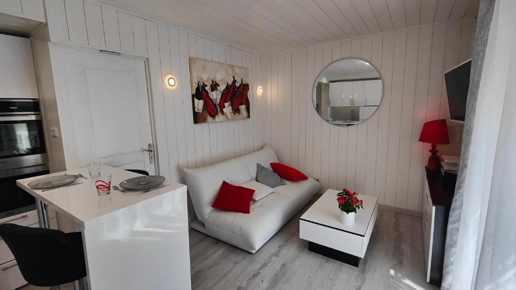 mały salon z białą kanapą i czerwonymi poduszkami w obiekcie Le Petit Paradis w mieście Brive-la-Gaillarde