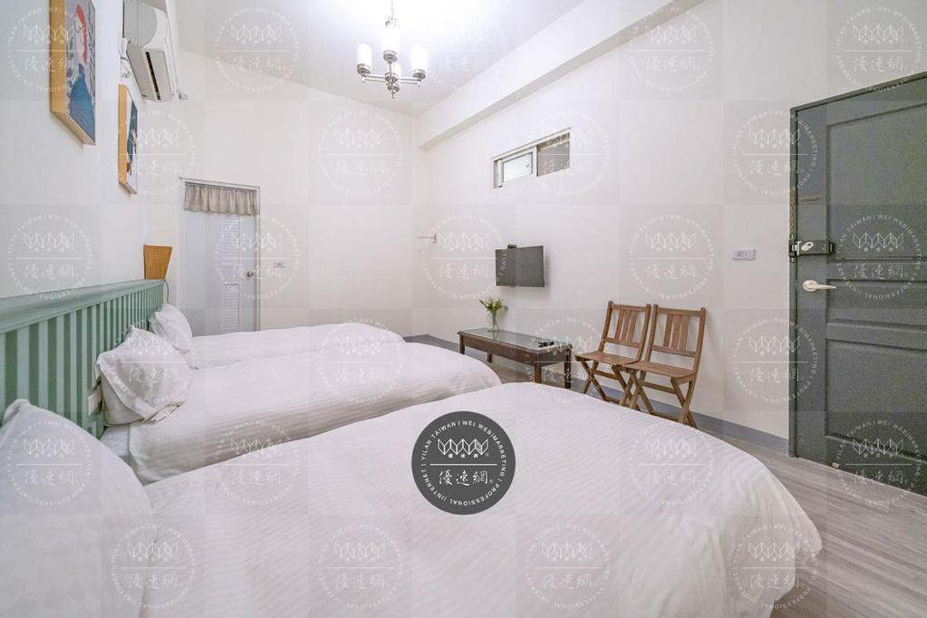 two beds in a room with white walls at 花蓮發現民宿-無人民宿自助入住-包棟可烤肉可麻將 in Hualien City