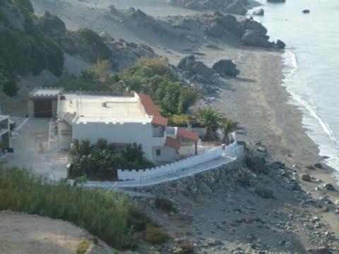 a house on a beach next to the ocean at VILLA SISSY in Agia Paraskevi