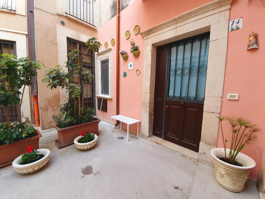 a door of a building with potted plants and a bench at One Love Ortigia in Syracuse