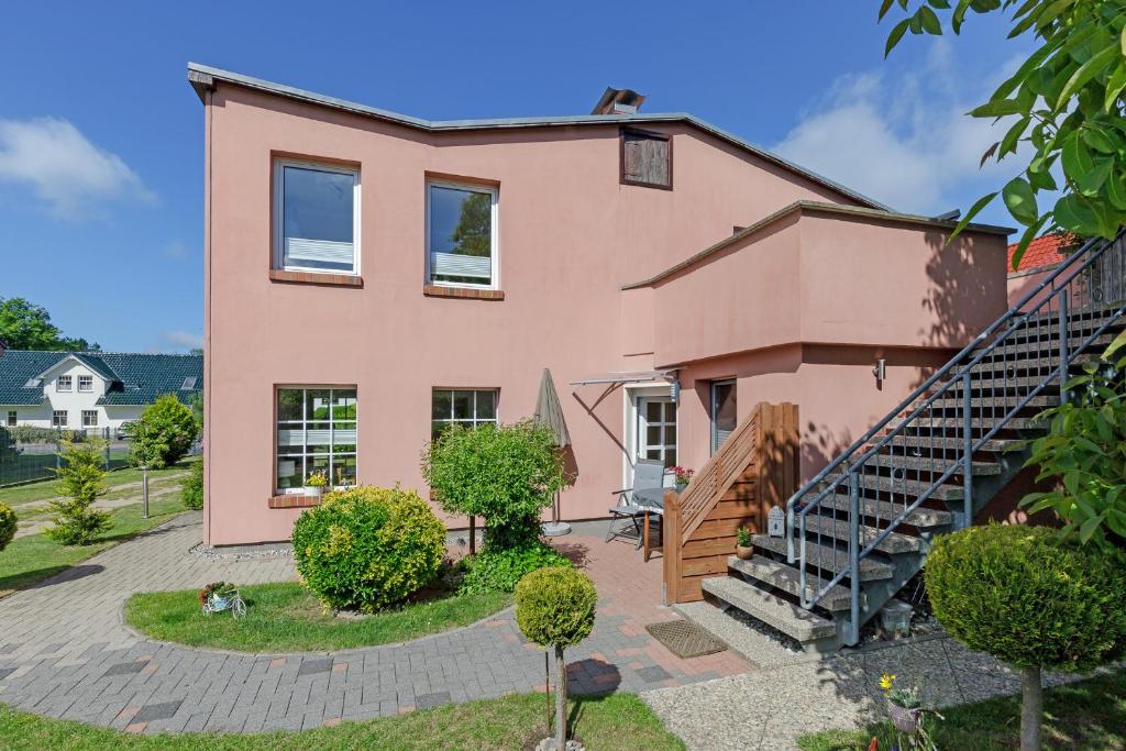 une maison rose avec un escalier devant elle dans l'établissement Ferienwohnungen Becker "Sonne & Meer" und "Strandliebe", à Kühlungsborn