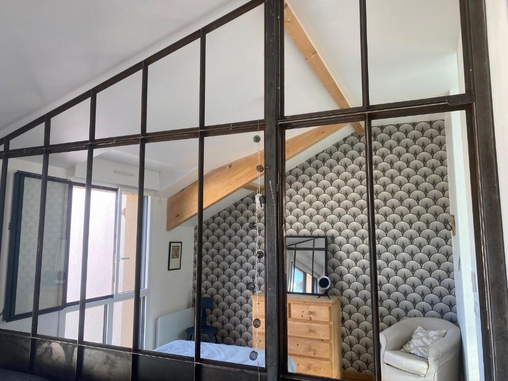 Cette chambre est dotée d'une grande paroi en verre avec un miroir. dans l'établissement Loft avec terrasse pour 4 pers à 3km du circuit avec garage au calme, au Mans