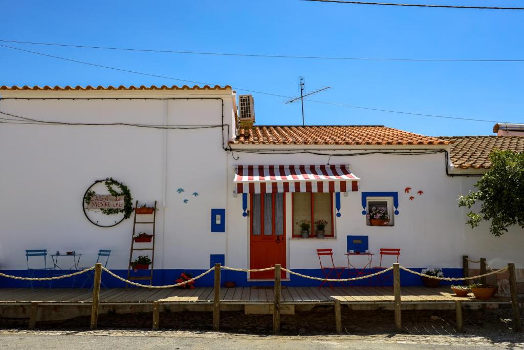un edificio blanco con toldo rojo y blanco en A Casa do Mestre Lau - no coração do Alentejo, en Terena