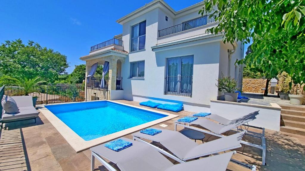 a villa with a swimming pool in front of a house at Luxury apartment Viktorija with private pool in Čižići