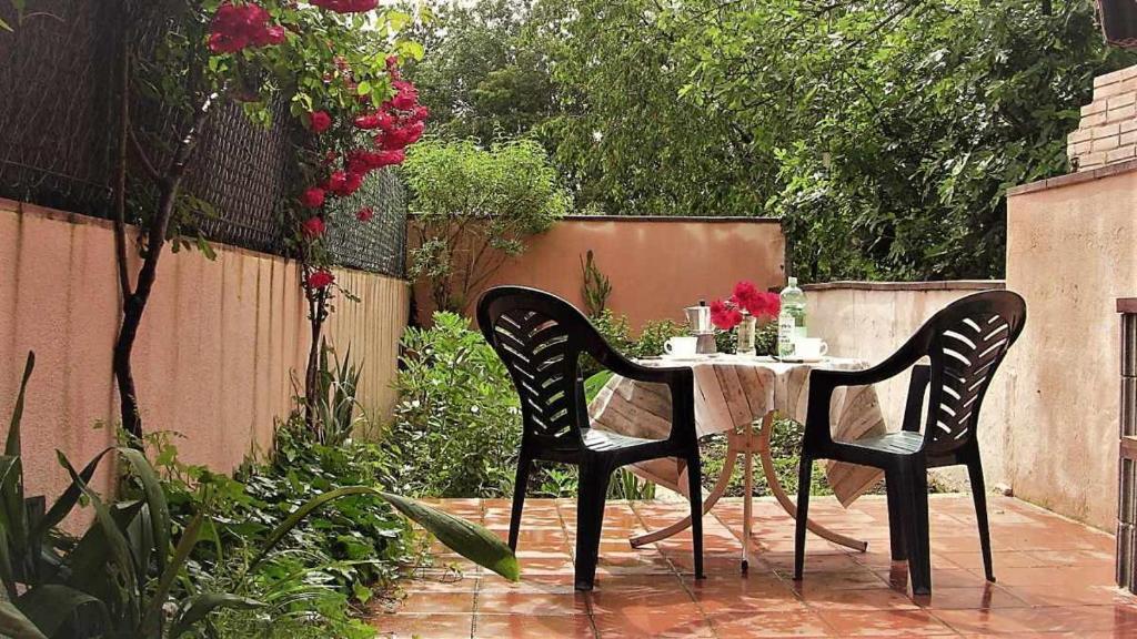 una mesa y sillas en un jardín con flores en Ca lEsperrucat Acogedora casa de pueblo Tranquila y bien comunicada, en Argelaguer