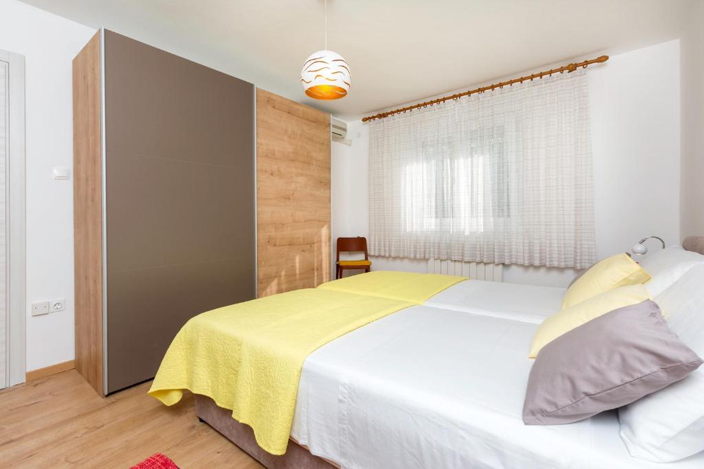 1 dormitorio con 1 cama blanca grande con manta amarilla en Apartment Vivid, en Pula